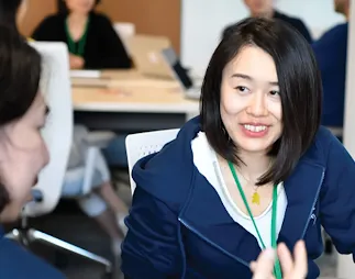 A woman in focus is smiling at other woman while sitting on chair