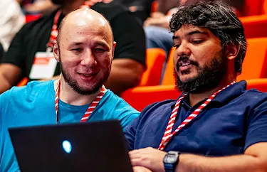 Two audience members are engrossed in a laptop.