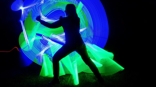 person in a defensive position in front of green and blue color swirls