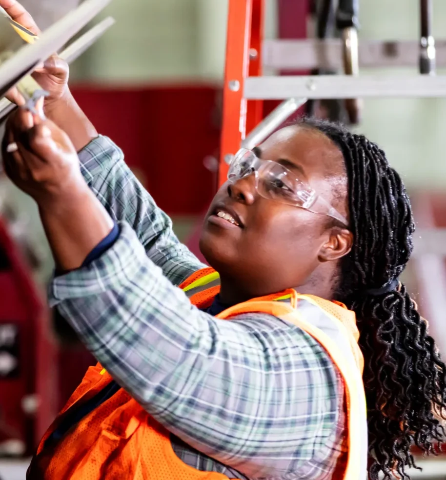 Woman working with a large tool. On the left are the Google and MIT FutureTech logos