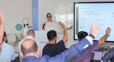 In a happy setting, the host is presenting, and attendees are raising their hands, ready to answer.