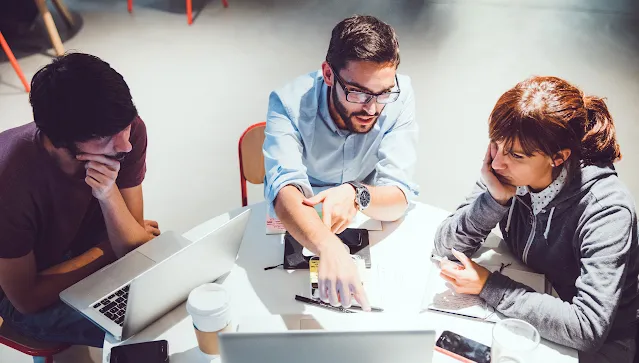 One women and two men are  looking at laptop.