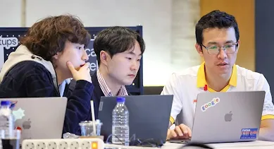 Three professionals collaborating on a laptop at a networking event.