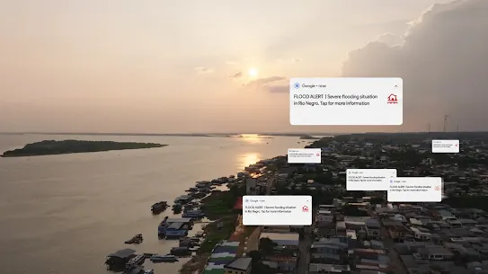 An aerial view of a coastal or riverfront town at sunset, with Google notification cards overlaid on the scene. The main notification card reads: "FLOOD ALERT | Severe flooding situation in Rio Negro. Tap for more information." Additional identical, smaller notification cards are scattered over the cityscape. The background shows a wide river, a sunset reflecting on the water, and densely packed buildings along the shoreline.