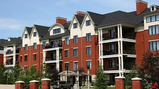 A modern condominium building featuring red brick siding, white gables and several private balconies.