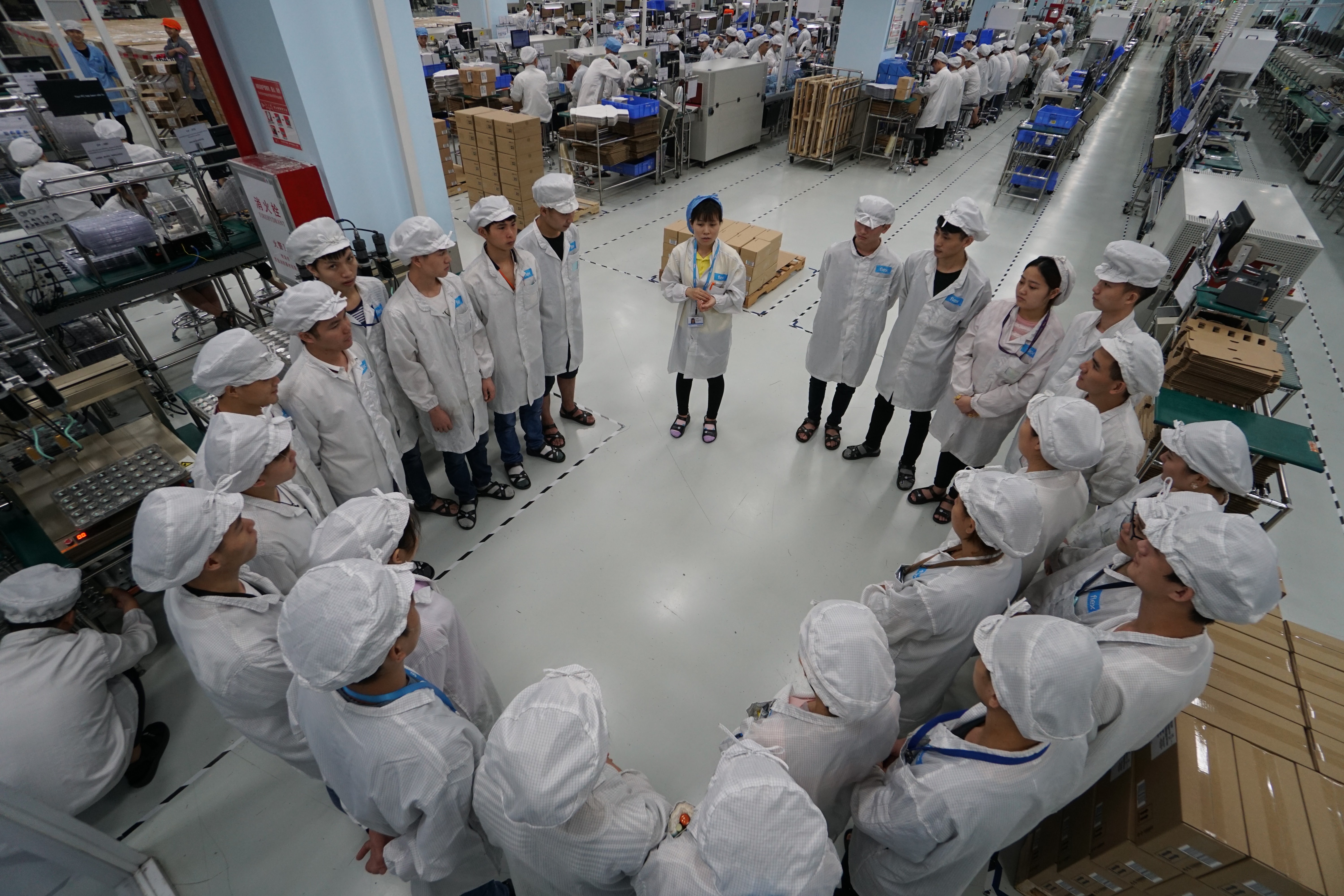 A group of workers meeting on a factory floor.