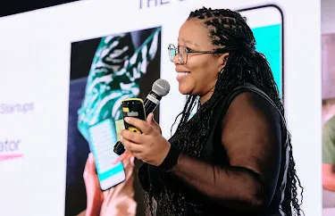 With a mic in one hand and her phone in the other, the woman leads the event and engages the crowd.
