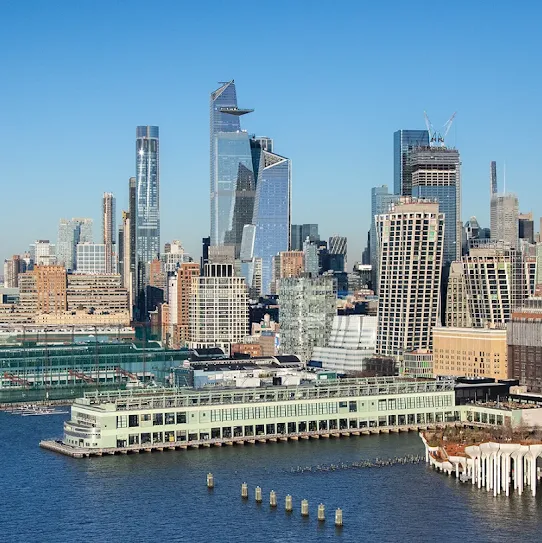 Panoramic view of the New York City skyline and Hudson River waterfront, featuring Pier 57, Little Island, and Hudson Yards skyscrapers under a clear blue sky