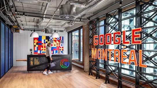 A person walks by a front desk in an office lobby with a colorful flag-like art piece. To the right, large red and orange neon letters spell out "Google Montréal."