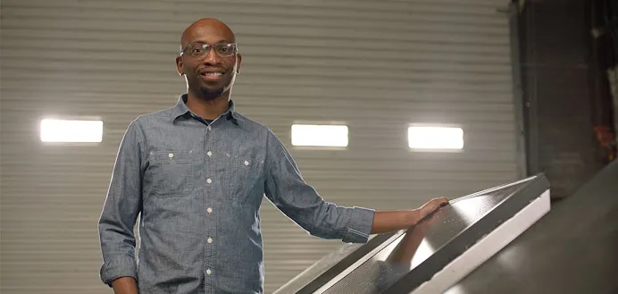Founder Seyi Fabode smiles at the camera inside his garage-turned-office.
