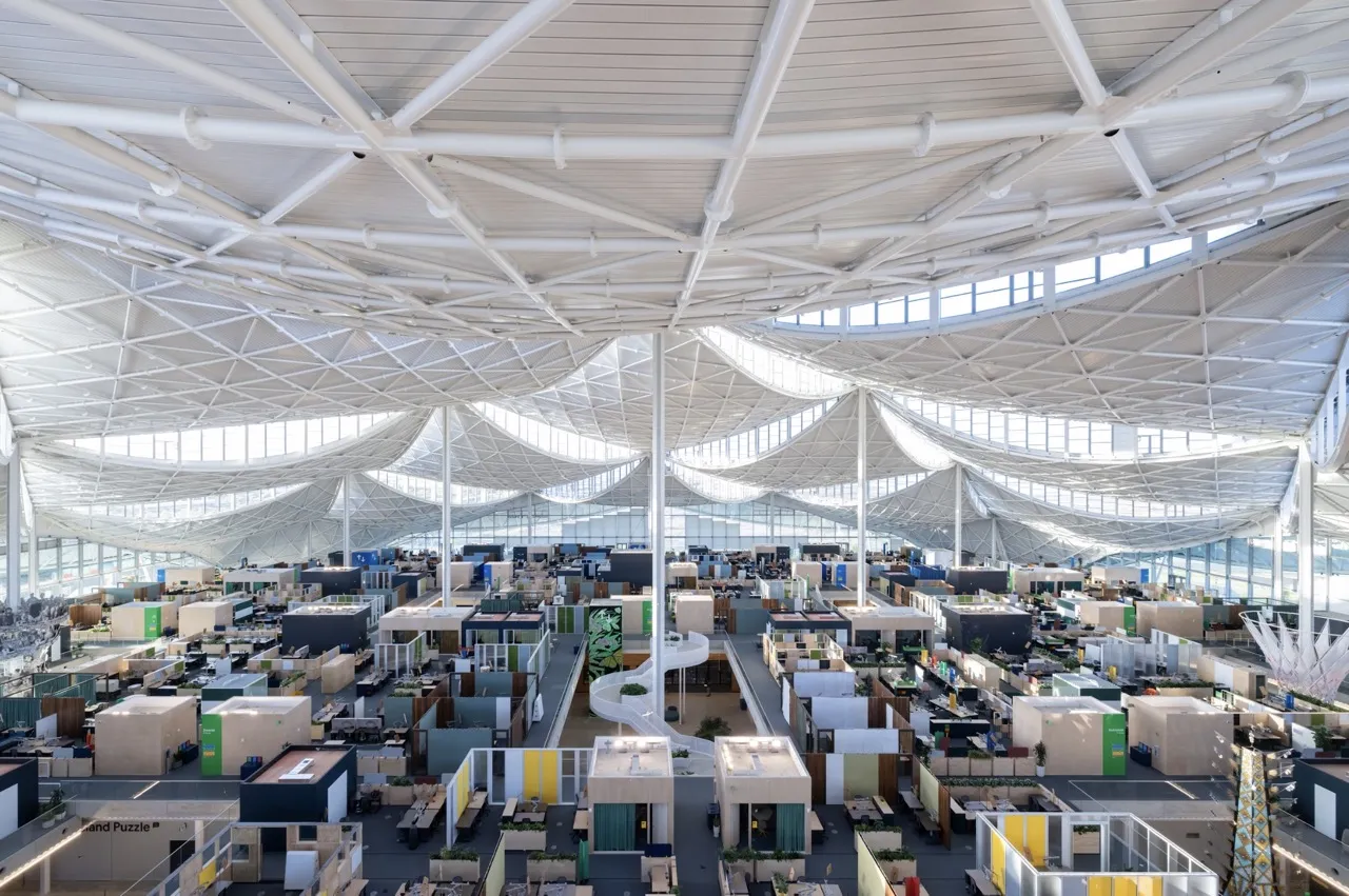 Vista aérea del espacio de trabajo del segundo piso en Bay View muestra cómo miles de Googlers pueden estar en un espacio conectado con vecindarios de equipos individuales bajo un dosel inspirador.