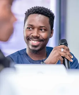 A man holding a mic and smiling.