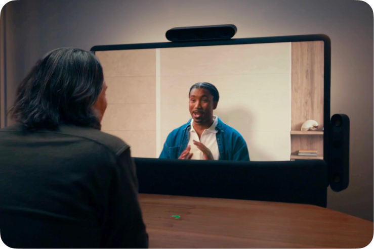 Two people meeting through a previous version of the Google Beam device.