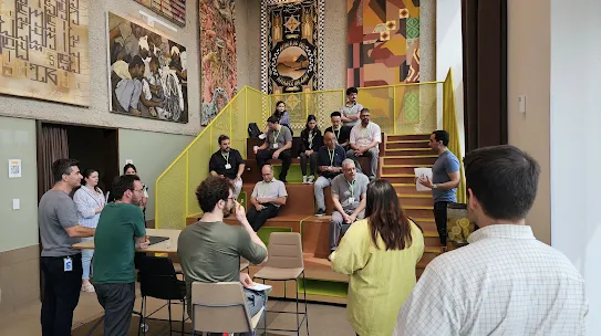 A leader talks to a group of people who sit on risers and chairs during a discussion. 