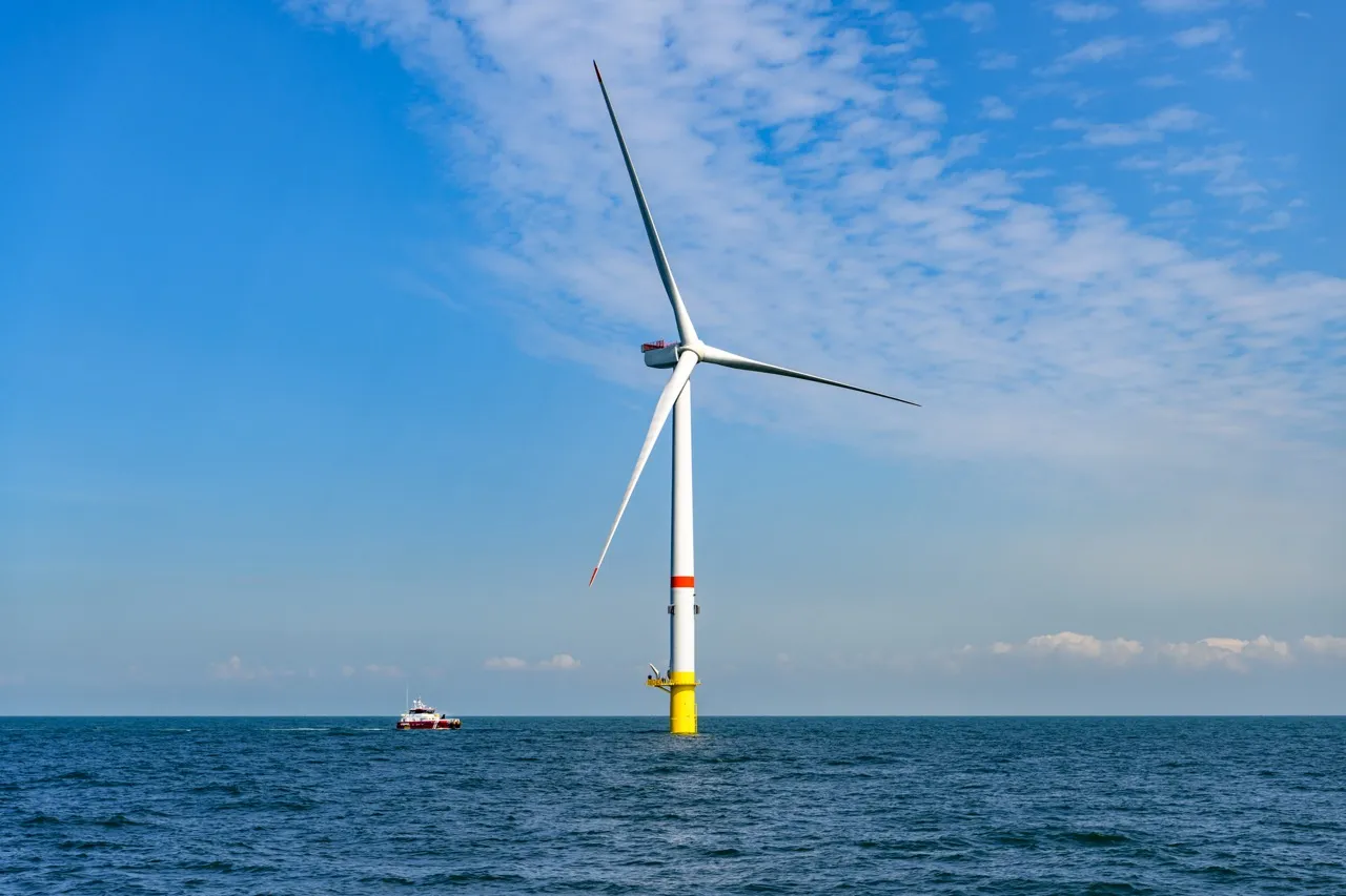 Une éolienne en mer, avec un ciel bleu azur en arrière-plan