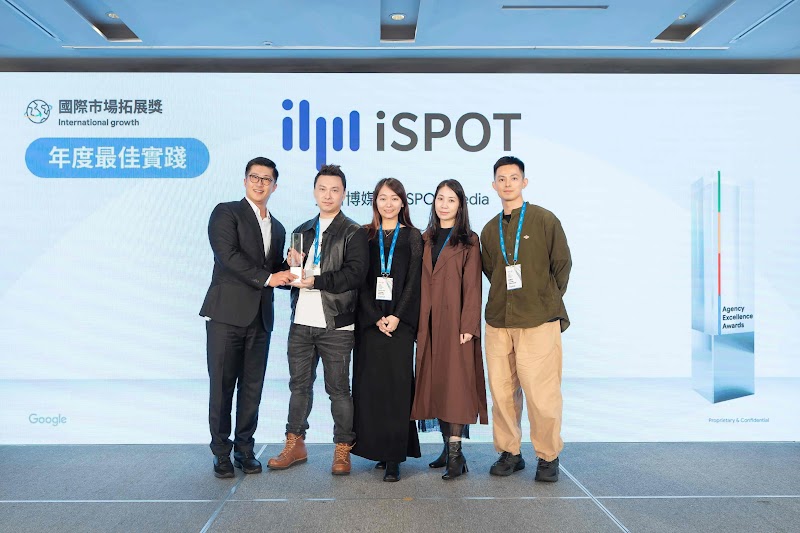 五位業界人士站在藍色背景前領取 Google Agency Excellence Award。背景文字顯示「國際市場拓展獎：年度最佳實踐」，左上角有「國際市場拓展展獎」與「年度最佳實踐」標誌。右側為 Google 獎項標牌。此獎項表彰 iSPOT Media 艾斯博媒體如何透過資料驅動策略，協助亞立詩在香港、新加坡等海外市場快速建立品牌知名度與市場觸及。