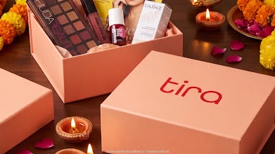 A peach Tira beauty gift box filled with makeup and skincare products, surrounded by lit clay diyas and festive marigold flowers