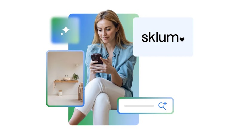 Mujer rubia de pelo largo usando su móvil, con camisa vaquera y pantalón blanco sobre fondo azul y verde. A su lado aparecen elementos gráficos: barra de búsqueda, estrella de IA, el logo de Sklum y un lavabo moderno.