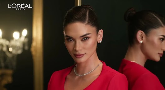 The video thumbnail shows a stunning woman, likely a celebrity or model, dressed in a red outfit and wearing a diamond necklace and stud earrings. She is looking directly at the camera in a glamorous setting, with the L'ORÉAL PARIS logo visible in the upper left corner.