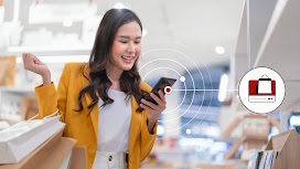 A woman holding multiple shopping bags uses her phone in-store, representing how data-driven Online-Merge-Offline (OMO) marketing and omnichannel retail strategies can help retailers like Muji maximise sales