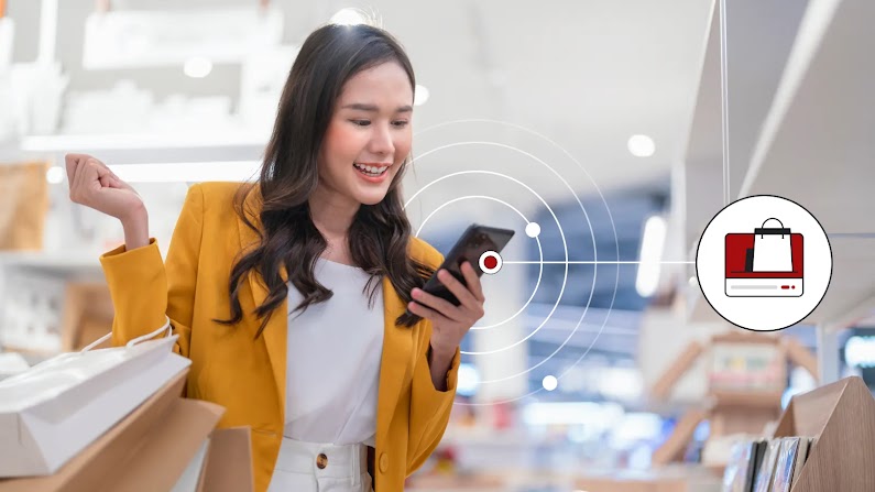 A woman holding multiple shopping bags uses her phone in-store, representing how data-driven Online-Merge-Offline (OMO) marketing and omnichannel retail strategies can help retailers like Muji maximise sales