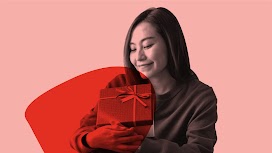 一位穿毛衣、戴毛線帽的女性面帶微笑，拿著兩份節慶禮物。