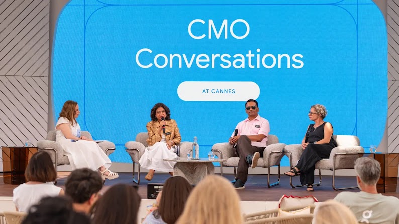 CMOs from L’Oréal, Zillow, and Back Market sit on stage in casual clothing for a Google-hosted panel discussion at the Cannes Lions Festival, entitled CMO Conversations at Cannes, which appears on a large, turquoise screen behind them.
