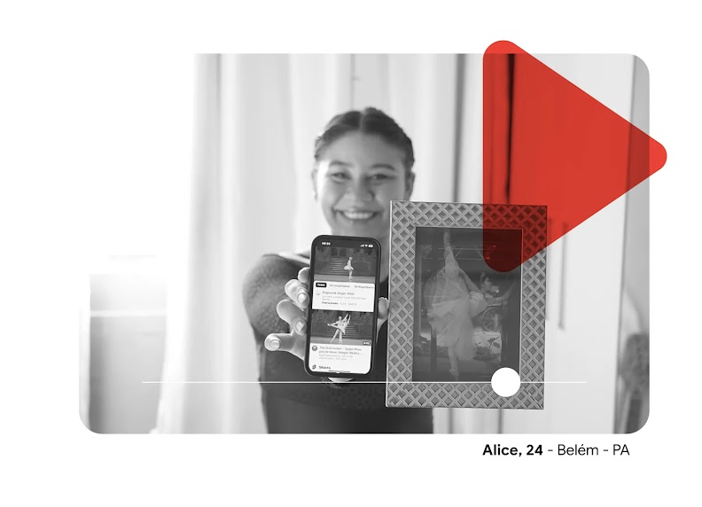 Imagem em P&B de Alice segurando o celular na tela com vídeos de balé e uma foto sua vestida de bailarina dançando. A imagem possui o símbolo de ‘play’ em vermelhor sobreposto.