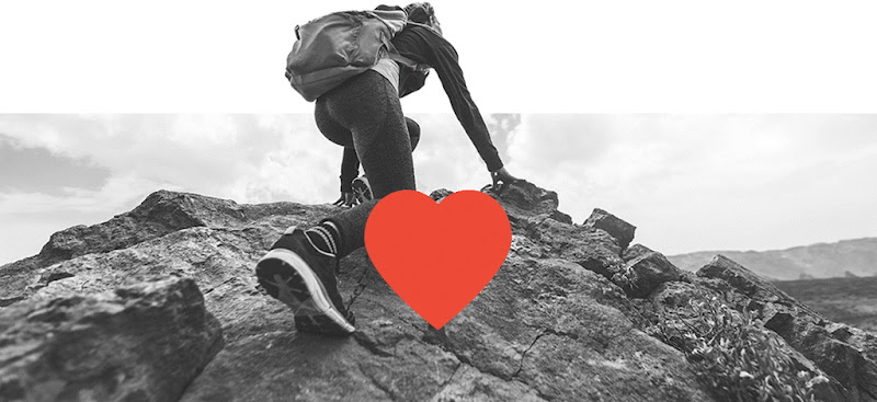 A heart overlaying a hiker climbing up a rocky terrain