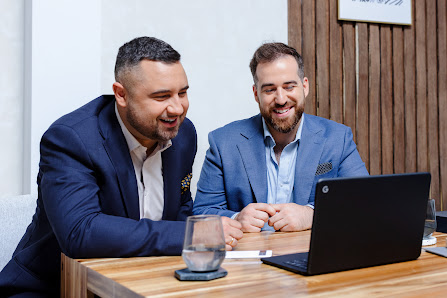Dos personas miran una laptop y sonríen. Un botón que dice “15x retorno de la inversión publicitaria” aparece debajo de ellas.