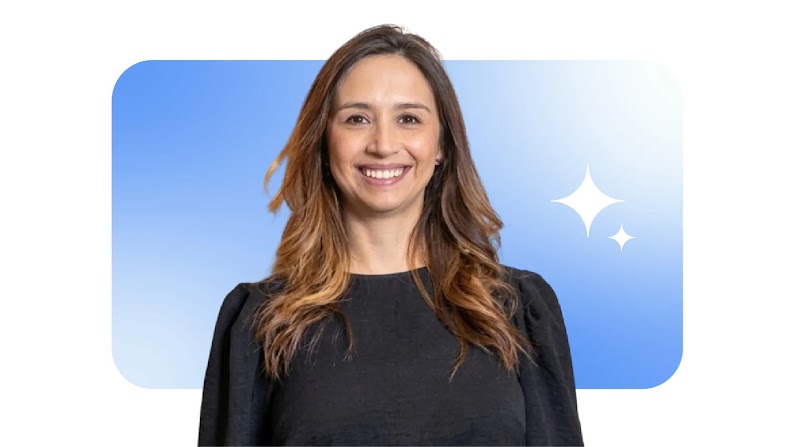 Fotografía de una mujer sonriente con cabello largo castaño y blusa negra. Es Carolina Avella, CMO de Google México. De fondo, un recuadro azul degradado con bordes redondeados y dos destellos blancos a la derecha.