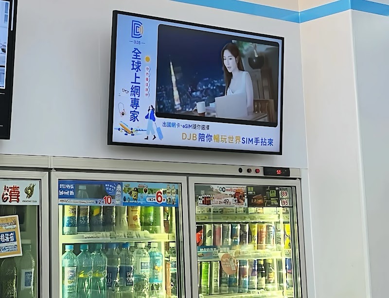 7-ELEVEN 門市內，數名顧客於冷藏冰櫃前選購飲料，上方壁掛數位看板播放品牌人物廣告，透過 Google Marketing Platform 與 DV360 程序化廣告投放，呈現 DOOH 線下曝光接觸點。