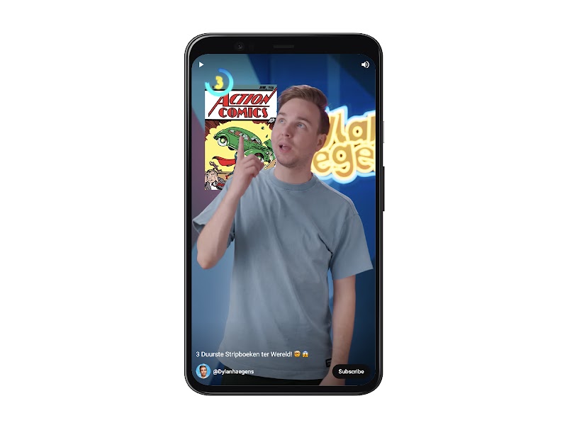A mobile device with a YouTube Short video playing fullscreen. Dylan Haegens stands, pointing at text that reads “Action Comics.” In the top left corner, a timer reads “3.” At the bottom, the caption, account username, and a “Subscribe” button.