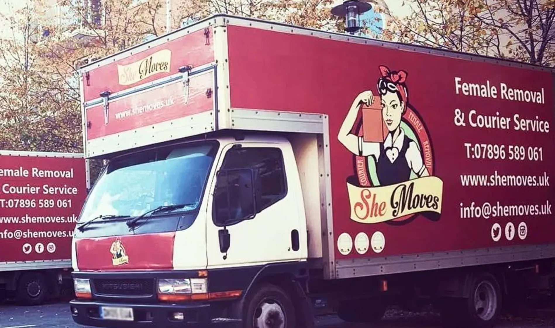 She Moves moving trucks are parked in a residential neighborhood.