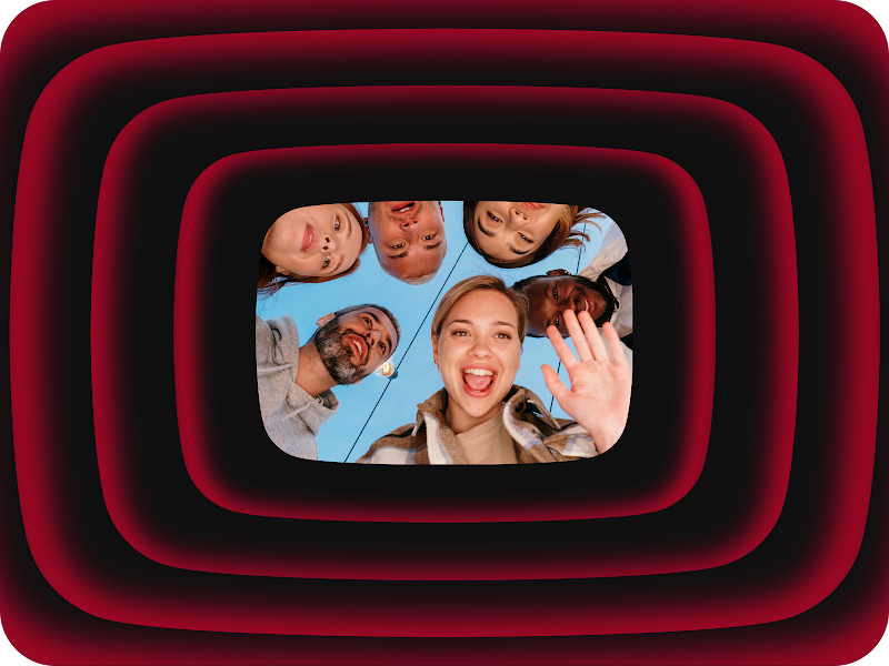 A diverse group of friends huddles together, smiling and waving down at the camera.