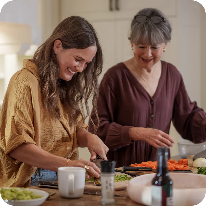 Two women smiling and laughing together while preparing a meal in a bright, modern kitchen. A stat callout reads  “3x sales” and overlays the image.