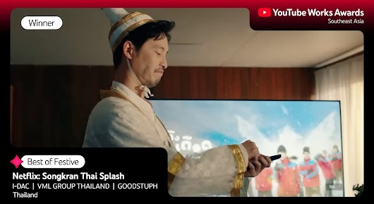 A man wearing white and gold traditional Thai attire, including a pointed hat, standing in a living room and holding a remote control. A TV screen behind him shows people playing in water. The overlay text reads: "Winner," "Best of Festive," and "Netflix: Songkran Thai Splash," followed by agency names and "Thailand."