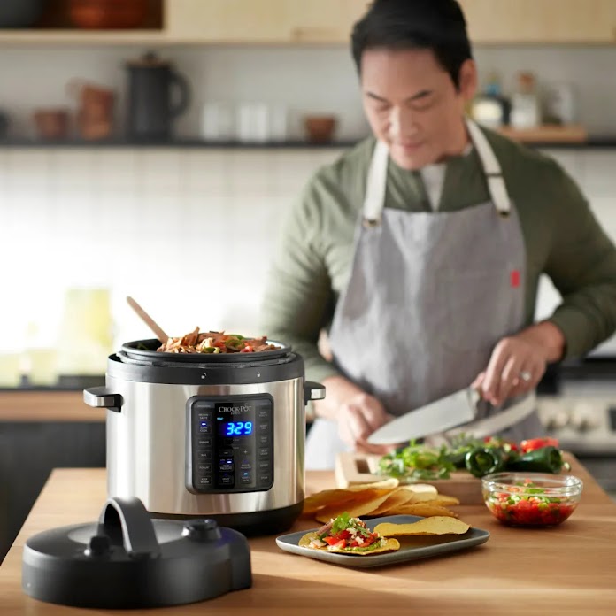 Một người đầu bếp đeo tạp dề đang nấu ăn trong bếp với chiếc nồi Crockpot thông minh ở tiền cảnh.