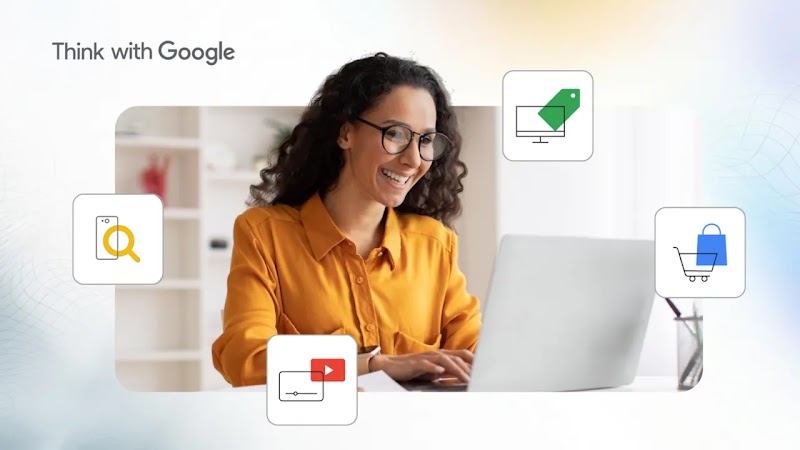  Mulher de cabelos cacheados, óculos e camisa amarela usando um computador, com ícones de busca, compra, promoção e vídeo.