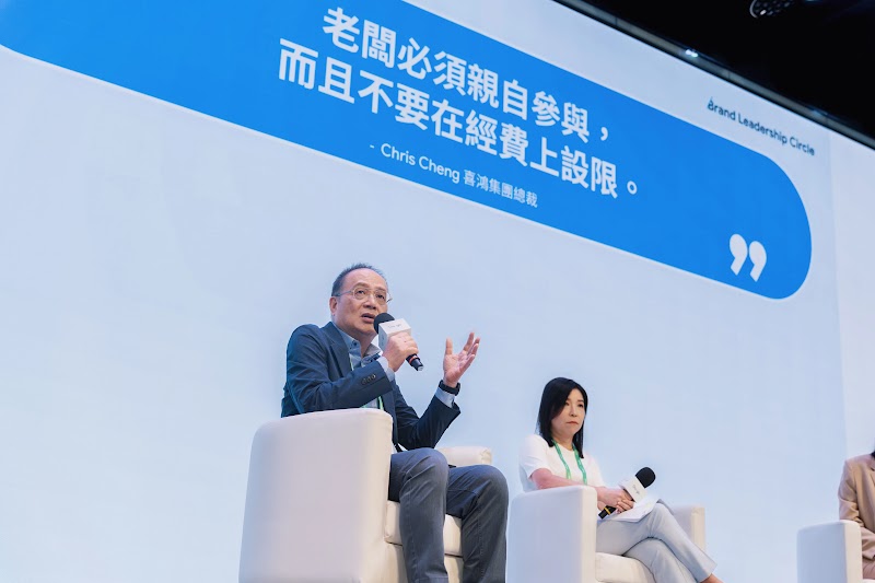 Brand Leadership Circle 活動現場照片，男講者坐在白色沙發上手持麥克風發言，背景大型螢幕顯示引言『老闆必須親自動參與，而且不要在經費上設限。』