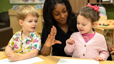 A teacher working with two young kids.