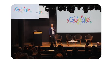Photo de Jean Philippe Bécane directeur marketing de Google France sur une scène lors d'une conférence. Des écrans affichent le logo Google.