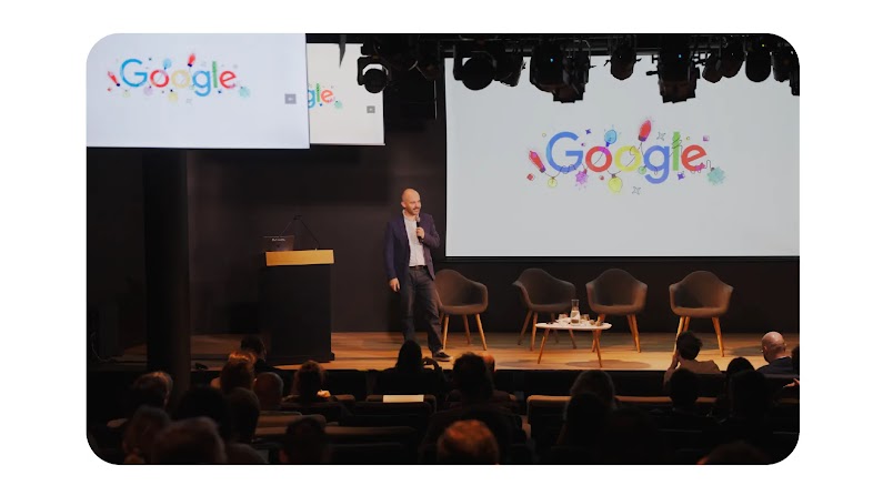 Photo de Jean Philippe Bécane directeur marketing de Google France sur une scène lors d'une conférence. Des écrans affichent le logo Google.