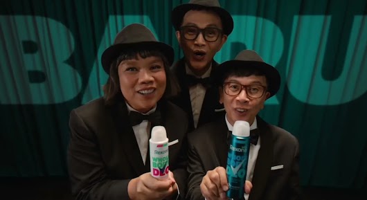 A video thumbnail of three men in matching tuxedos and fedoras smiling enthusiastically while holding up two aerosol spray cans.