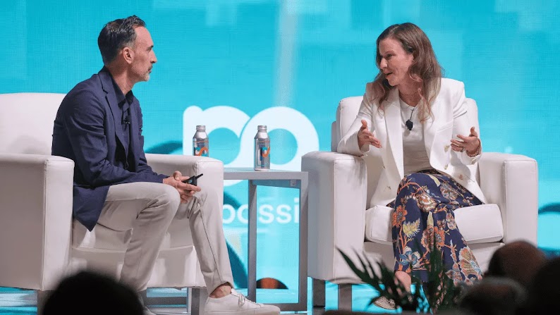 Sean Downey, président d'Americas & Global Partners chez Google, est assis à côté de Laura Jones, CMO d'Instacart, sur la scène de la conférence "Possible Miami", devant un arrière-plan bleu vert, décoré d'un paysage urbain et de palmiers.