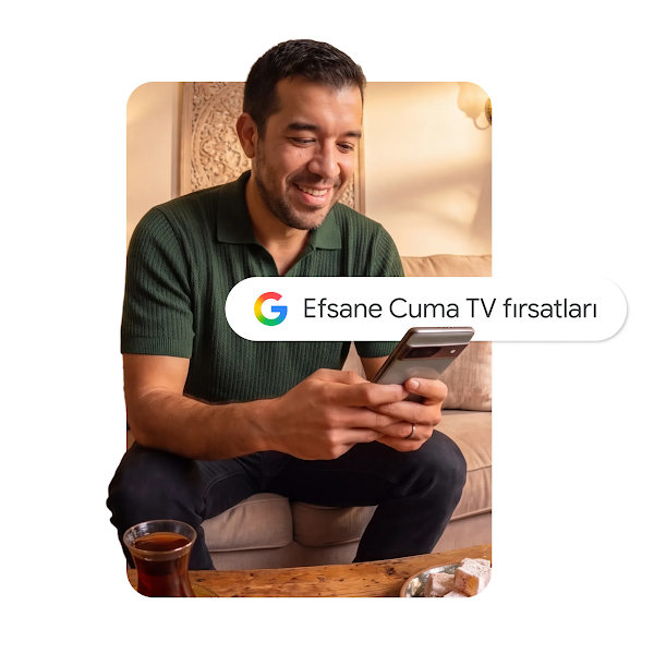 Kanepede oturan, "Black Friday TV fırsatları" yazan bir Google arama çubuğu katmanına sahip akıllı telefon kullanan gülümseyen bir adam grafiği.