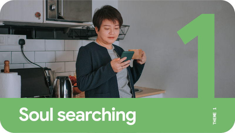 Theme 1: Soul searching. A person using a mobile phone for Search and holding a cup of coffee while standing in the kitchen.