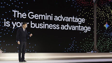 Philipp Schindler speaks from a stage with a large screen behind him. The screen has a black background with rainbow sparkles surrounding the text: The Gemini advantage is your business advantage.