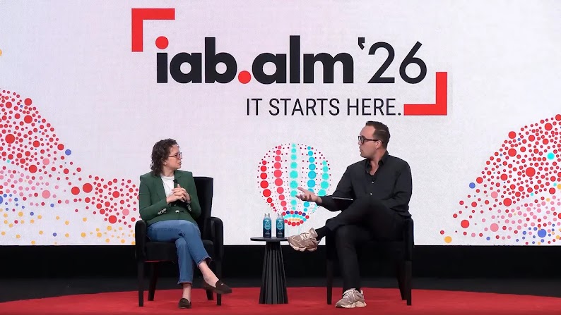 Liz Reid, VP of Search at Google, and Alex Heath, founder of Source, sit in chairs in front of a large pink screen with multicolored dots that reads iab.alm ’26 it starts here.