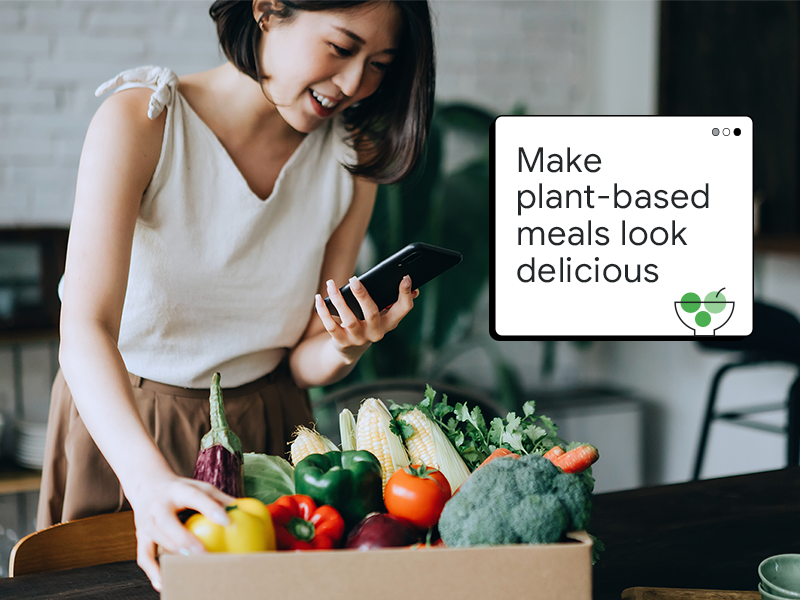 A woman with light skin and dark hair checks a box of colorful vegetables against her delivery order on a mobile device. A pop-up window reads “Make plant-based meals look delicious.”